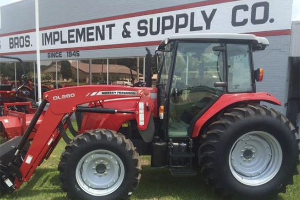 Massey Ferguson tractor parked outside Watts Bros Implement and Supply building with branded signage visible